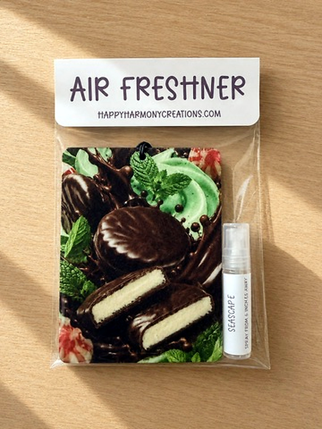 packaged rectangular air freshener with green dessert artwork and scent bottle