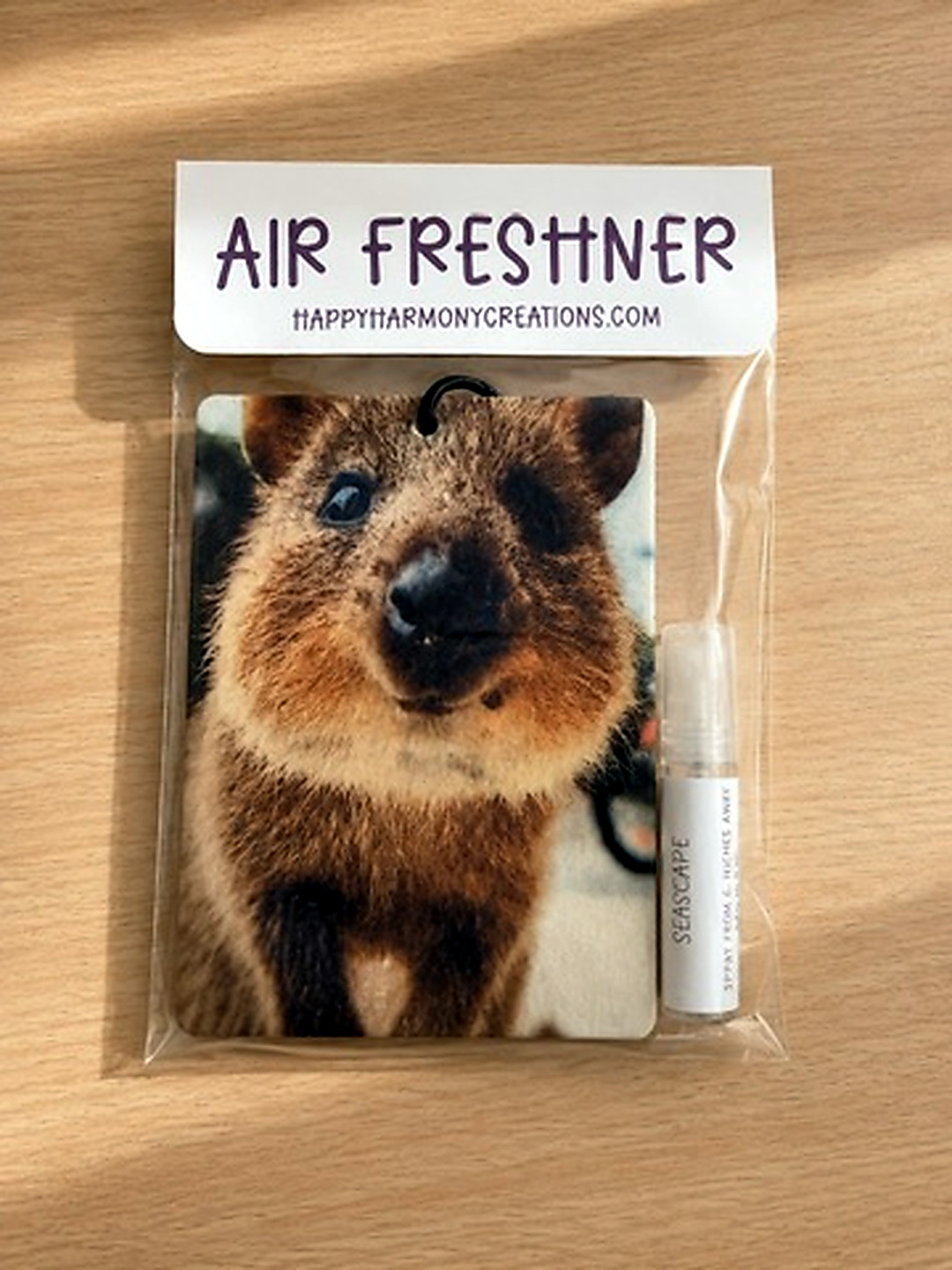 packaged rectangular air freshener with quokka portrait artwork and scent bottle